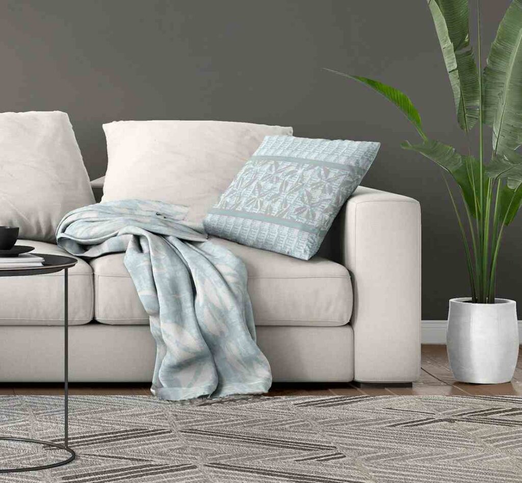 Gray wall and a white sofa with a blue color throw blanket and a pillow