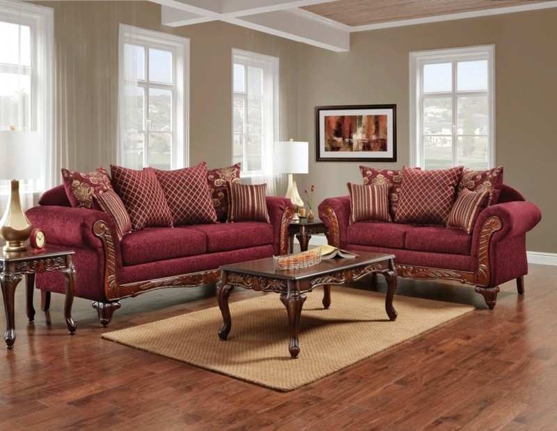 A wooden table and golden and burgundy color throw pillows on sofa