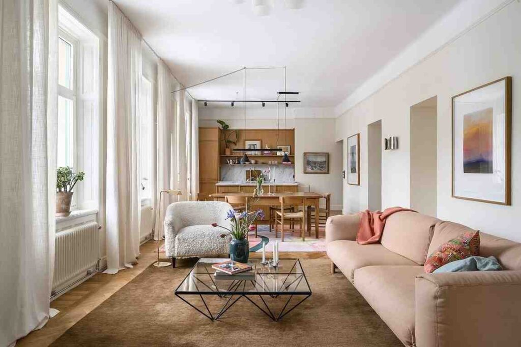 Pink sofa and cream color walls and wooden kitchen cabinets