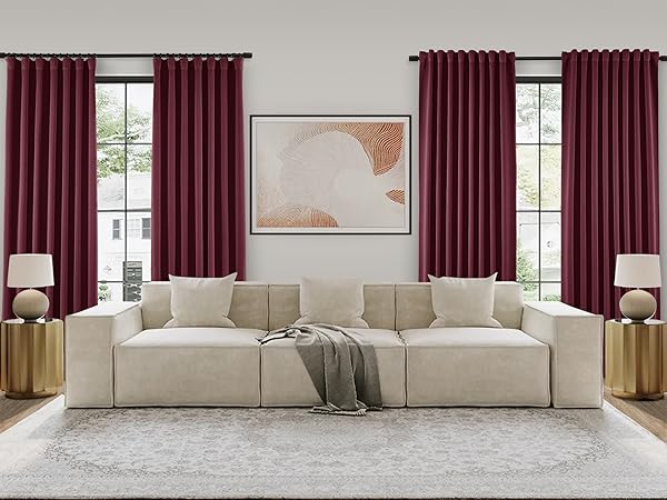 Plain burgundy color curtains and white sofa set with a grey blanket and a art frame