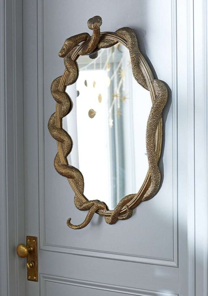 Golden color snakes in Design mirror on white wall panelling door