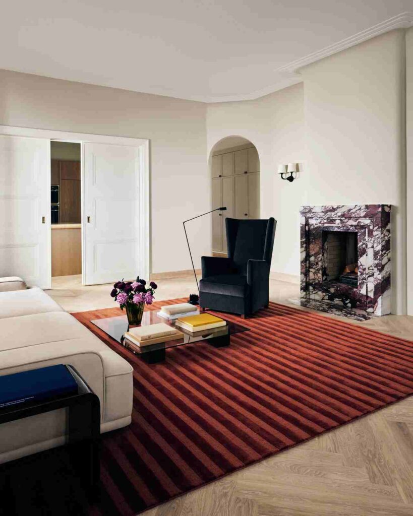 Striped pattern burgundy rug in living room and a black armchair