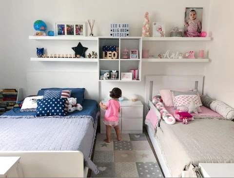 Two bed and floating shelves above it in white color and a girl standing between the bed