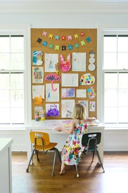Two-chair-and-a-cardboard-art-bulletin-board-on-wall-and-a-girl-seating-on-it
