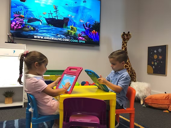 Two-kid-playing-on-digital-game-board-sitting-on-chair