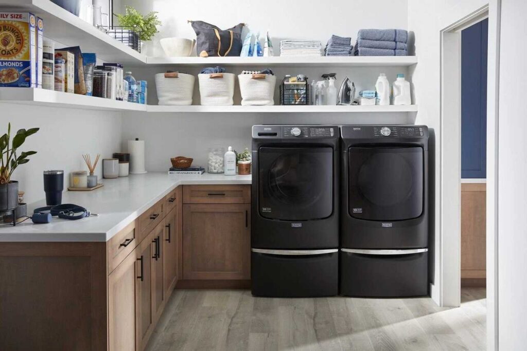 Two matte black color washing machine and white counter top with cabinet's