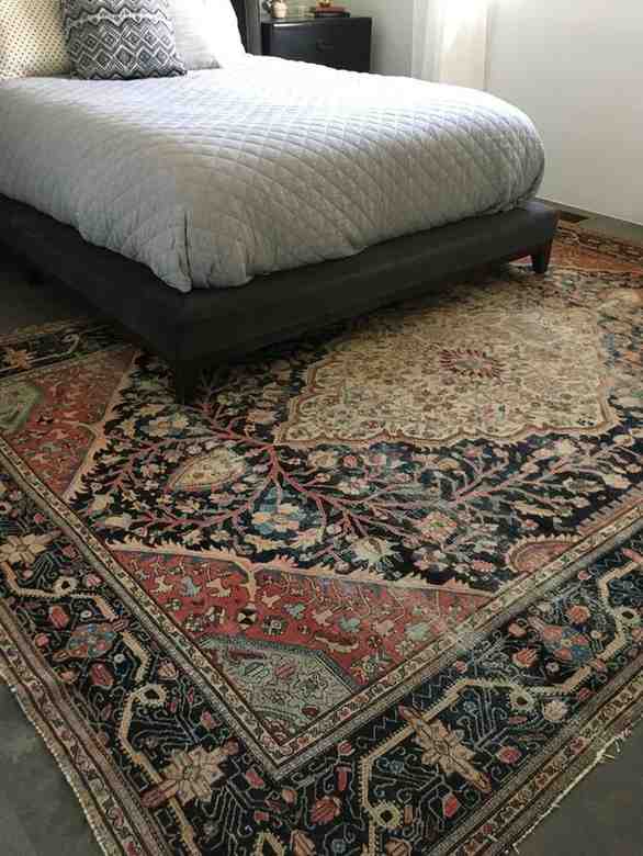 Dark grey color bed frame and a vintage boho style rug under it