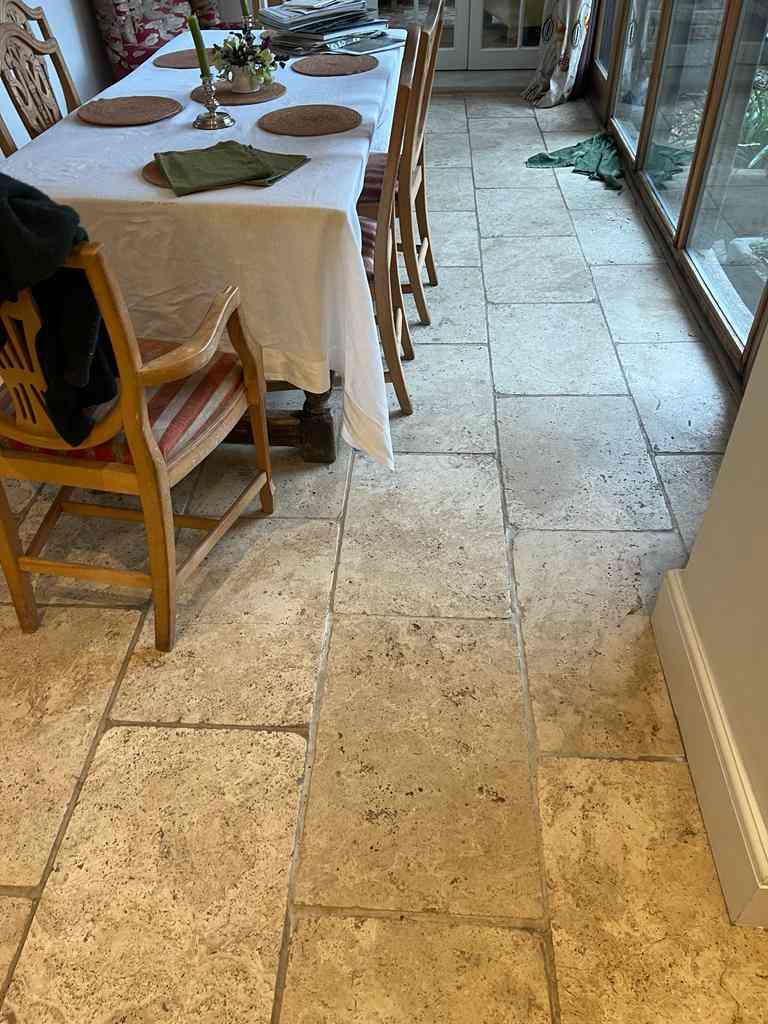 White travertine tile and wooden dining table set with a white clothe on it