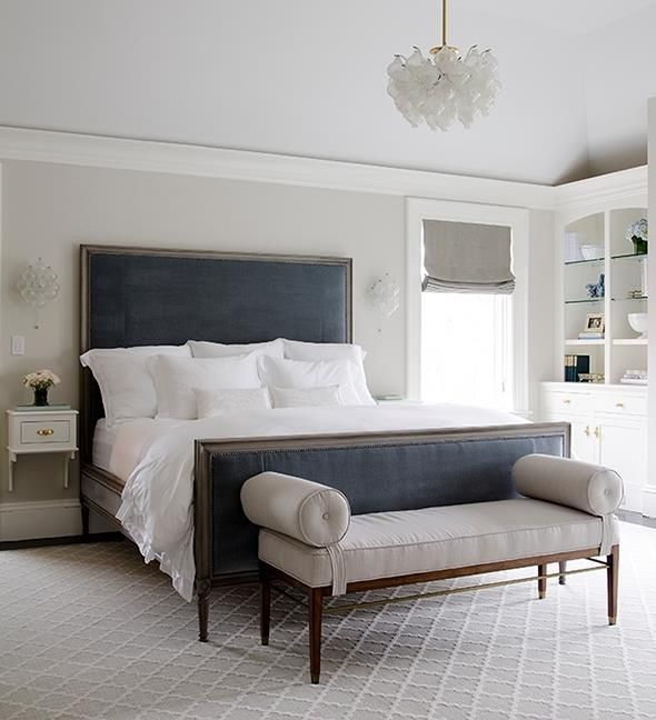 Wooden frame beige seating bench in front of the bed