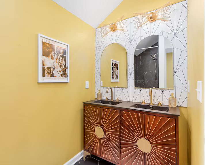 Yellow wall and a wooden basin cabinet and a white and black lined mirror backdrop
