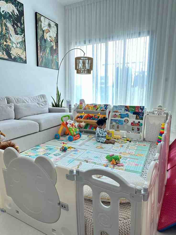 Sheer curtains on window and white and gray color playing pit for toddler filled with toys