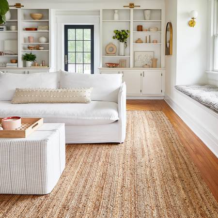 white sofa and a table with a jute rug under it