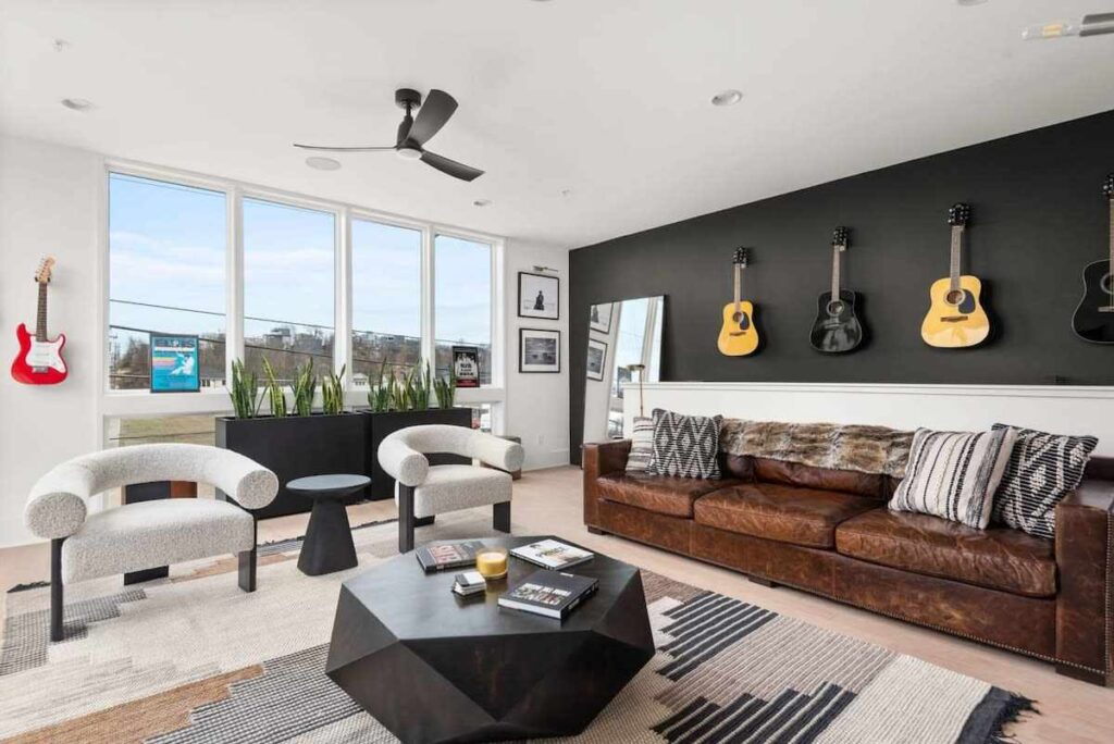 Brown leather sofa and two white chairs with a black center table 