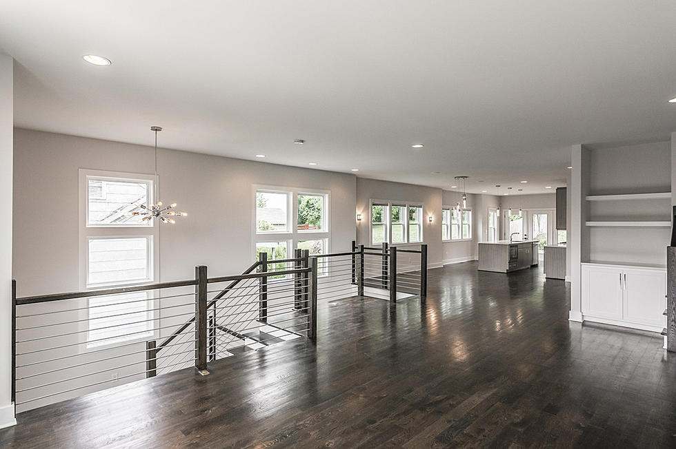 Black railing wooden flooring and white walls with open living room and kitchen