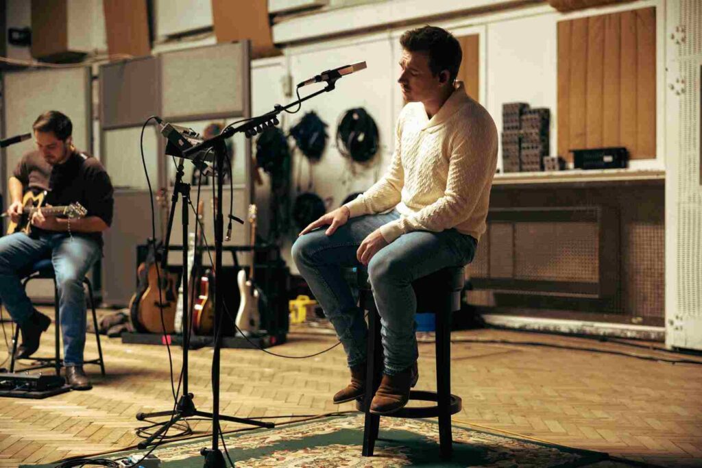 Morgan Wallen seating on a chair and singing in his music studio