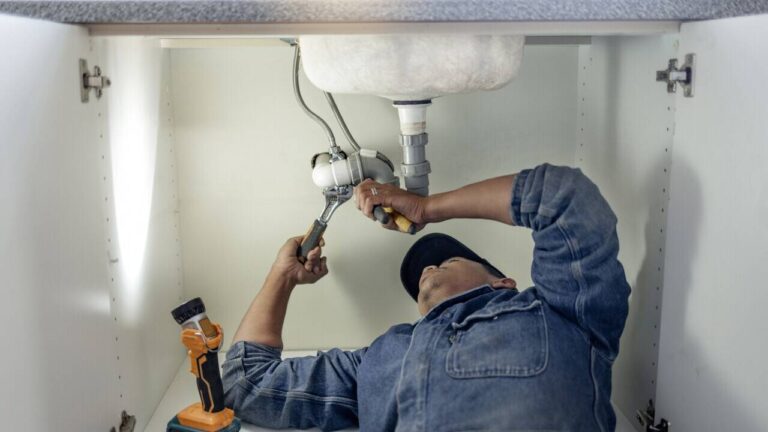 plumber-is-repairing-or-adjusting-pipes-and-valve-beneath-the-sink