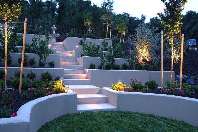 How to Transform Your Yard to Feel Like a Luxurious Space professional-landscaped-sloped-backyard-featuring-a-tiered-garden-design-and-incoporates-light-colored-retailing-walls