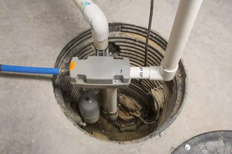 a-grey-control-box-mounted-on-a-vertical-pipe-and-black-float-ball-attached-to-a-rod-and-white-PVC-pipe-for-water-discharge-and-blue-pipe-connected-to-the-system