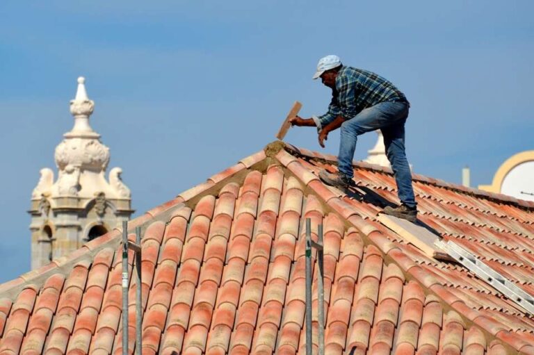 man-working-on-the-roof-of-a-building-the-roof-is-covered-with-curved-light-colored-tiles