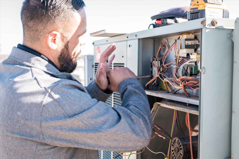 HVAC-technician-performing-maintenance-or-repairs-on-an-outdoor-heating-or-cooling-unit-the-technician-is-focused-on-the-internal-components-and-the-wiring-of-the-appliance