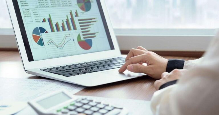 financial-data-and-charts-displayed-on-the-screen-and-appearing-as-a-digital-overlay-a-person-is-shown-tying-on-a-laptop-keyboard