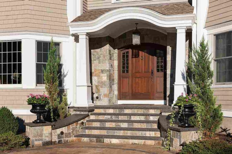 front-entrance-of-a-traditional-style-home-characterized-by-a-light-colored-exterior-and-a-prominent-arched-wooden-front-door