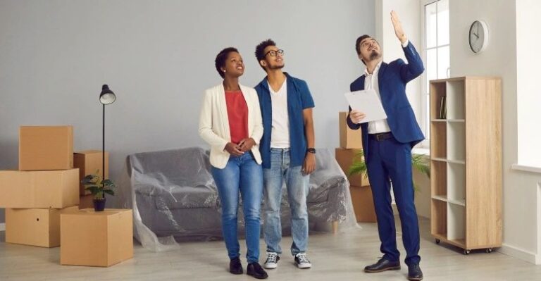 a-real-estate-agent-is-showning-an-apartment-to-a-young-couple-the-agent-is-pointing-toward-something-inside-the-room